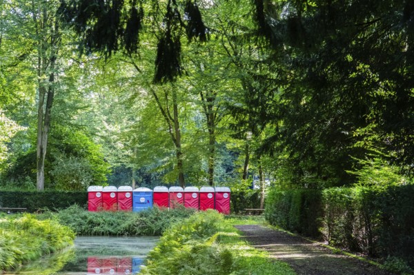 A row of red and blue toilet blocks in the park after an event, Düsseldorf, Germany, Europe