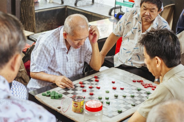 Chinatown, Singapore, June 21st 2015: Older Chinese men play Xiangqi, or Chinese Chess in a public space in SIngapore, Asia