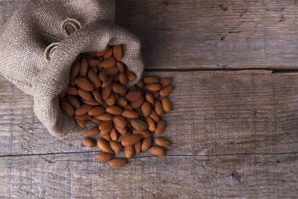 Almonds in a sack on old wooden board