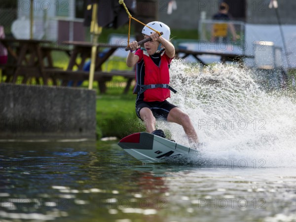 Boy or girl with wakeboard, fast ride on the water, water sports, water skiing in the wakepark