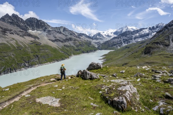 Mountaineer on a hiking trail at a blue mountain lake, reservoir Lac des Dix, behind mountain peak Mont Blanc de Cheilon, Hérménence, Valais Alps, Valais, Switzerland, Europe