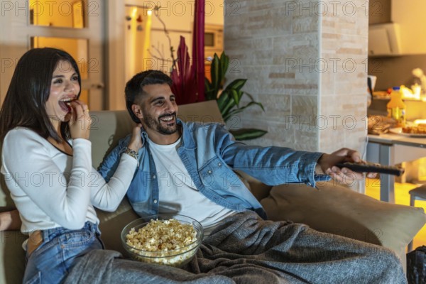 Young couple relaxing on a cozy sofa, enjoying a movie night filled with laughter, popcorn, and the warmth of togetherness