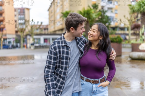 Young multiethnic couple sharing a joyful moment outdoors in a vibrant urban setting, showcasing diversity and connection in everyday life