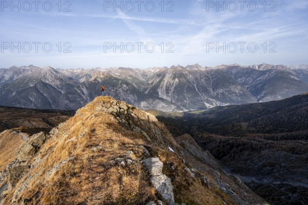 Mountaineer on the ridge in front of a mountain panorama, view from the ridge of the Venet to mountains of the Parzinn group in the Lechtal Alps, yellow larches in autumn, Venet crossing, Ötztal Alps, Tyrol, Austria, Europe