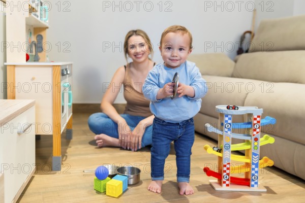 Adorable baby boy playing with a toy cymbal while mother sits on the floor, capturing a heartwarming moment of family bonding
