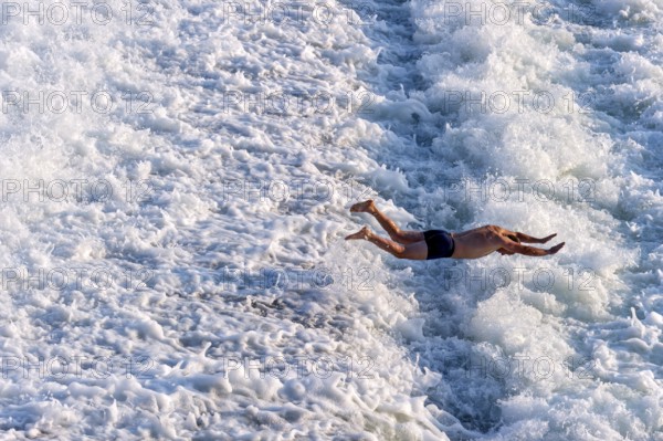 Man bathing in the spray of the Lech weir, jumping into the white foaming water of the cascades, river Lech, Landsberg am Lech, Upper Bavaria, Bavaria, Germany, Europe