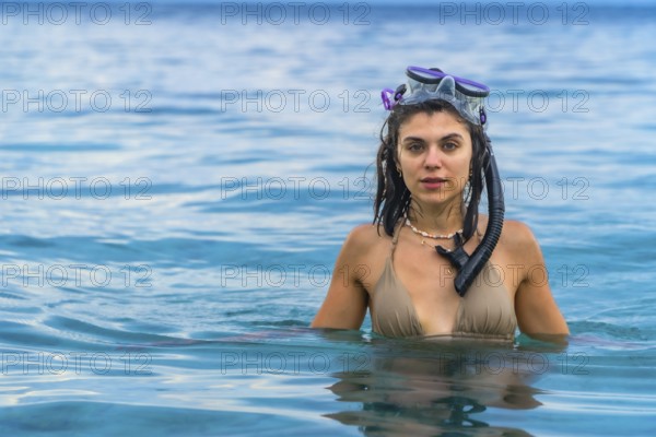 Young woman wearing snorkeling gear, swimming in the crystal clear waters of white beach, moalboal, on the island of cebu, philippines