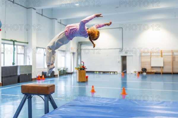 Girl practicing backflip in school gym, showcasing flexibility and athleticism during physical education class