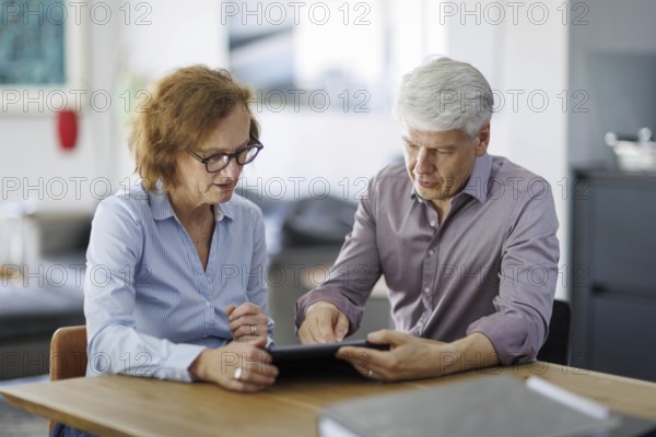 Symbolic photo. A woman and a man sit together at a table with a tablet and talk. Berlin, 13.08.2024