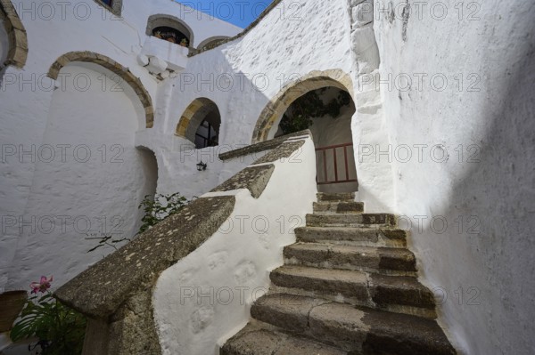 Stone staircase in a historic building with white walls and stone arches on a sunny day, Inside the monastery, Agiou Theologou Monastery, Chora, Patmos, Dodecanese, Greek Islands, Greece, Europe