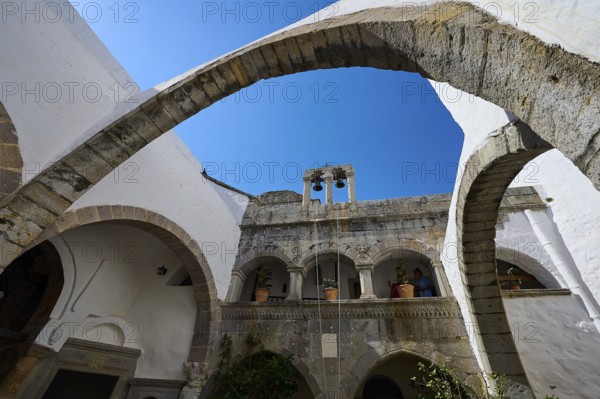 Historic monastery with stone arches and a bell tower under a blue sky, Inside the monastery, Agiou Theologou Monastery, Chora, Patmos, Dodecanese, Greek Islands, Greece, Europe