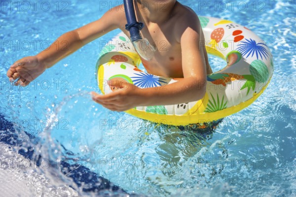 Part of a playful boy on a pool playing with colorful rubber ring