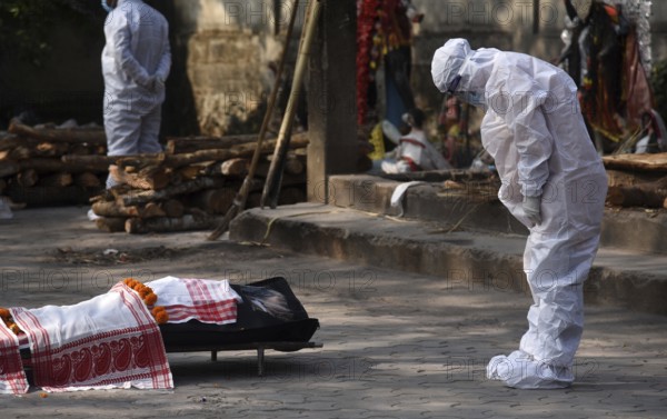 Family members wearing PPE kit performing last rites of a person who died of COVID-19 coronavirus disease, at a cremation ground in Guwahati, Assam, India on Saturday, January 29, 2022. India registered 250 thousand new coronavirus cases including Coronavirus Omicron Cases, in the last 24 hours, while 573 people died due to the infection