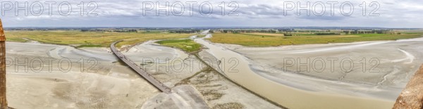 Extensive river landscape with sandbanks and green meadows under a cloudy sky, Le Mont-Saint-Michel