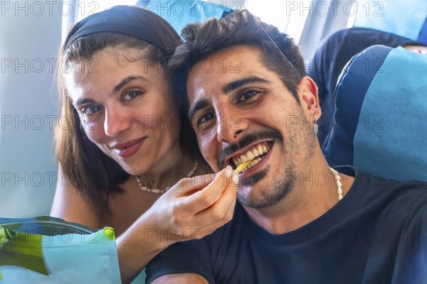 Young woman feeding french fry to her boyfriend while traveling by plane to coron island, philippines