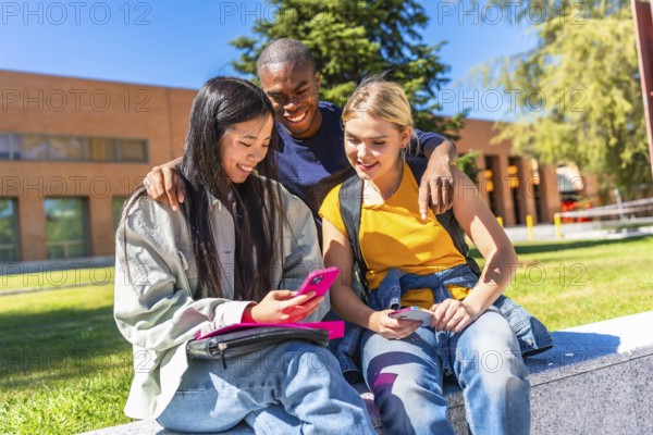 Happy mulit-ethnic group of exchange students using mobile outside the campus
