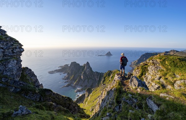 Mountaineer on the summit of Måtind or Måtinden, view of picturesque coastal landscape, rocky coast and sea, Andøya Island, Vesterålen, Nordland, Norway, Europe