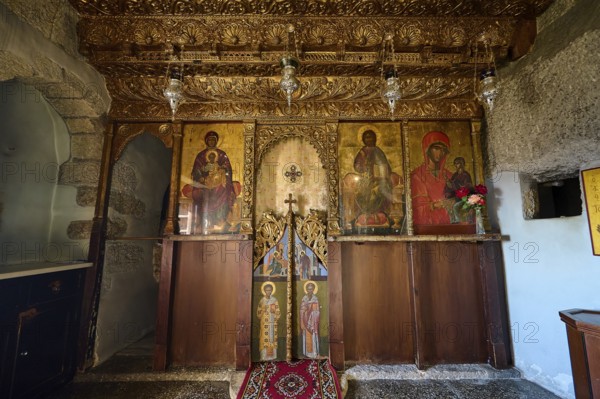 An altar in a church with religious icons, carved wood and candle lighting, Apokalipsis Monastery, Patmos, Dodecanese, Greek Islands, Greece, Europe