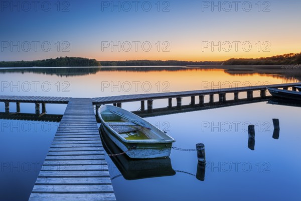 Wooden jetty with rowing boat at dusk, sunset on Lake Schaalsee, Mecklenburg-Western Pomerania, Germany, Europe