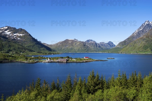 Landscape on the Lofoten Islands with sea and mountains. The Sildpollnes peninsula in the Austnesfjord with a church and a few houses. Good weather, blue sky. Early summer. Sildpollnes, Austvagoya, Lofoten, Norway, Europe