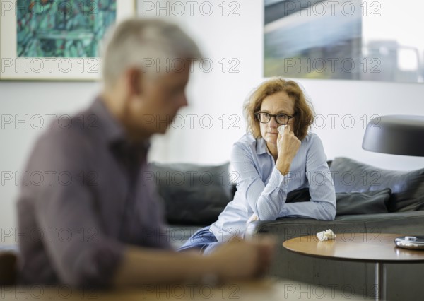 Symbolic photo on the subject of problems in a partnership. An older woman and an older man sitting at home. Berlin, 13.08.2024