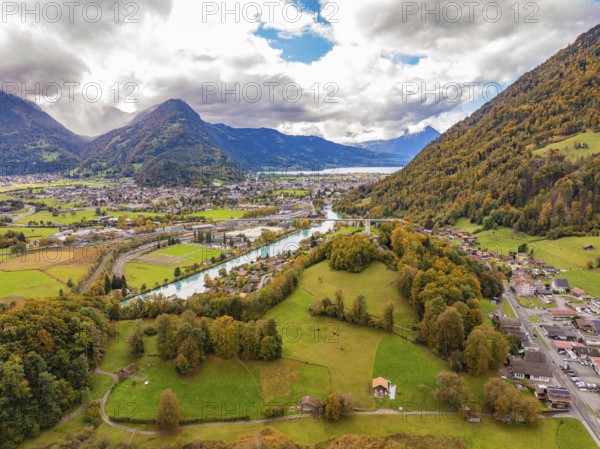 Panoramic view of a mountain landscape with meadows, river and a village under a cloudy sky, Interlaken, Switzerland, Europe