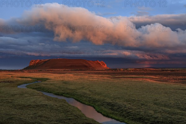 Volcanic crater reflected in stream, lava field, cloudy mood, midnight sun, summer, Burfellshraun, North Iceland, Iceland, Europe
