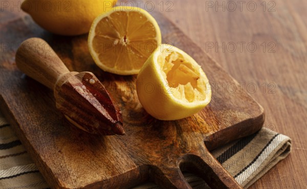 Lemons and a wooden manual citrus juicer, on a chopping board, close-up, no people