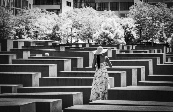Black and white photograph, woman in summer dress amidst the Holocaust memorial steles at the Brandenburg Tor, Berlin, Germany, Europe