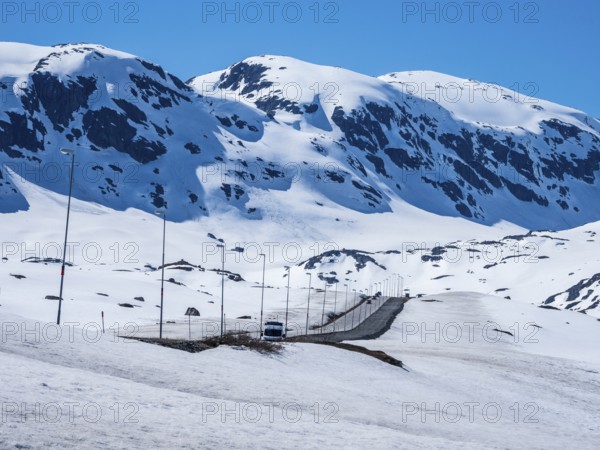 Camper van driving through snowy high mountain landscape, Haukelivegen road, E134, Norway, Europe