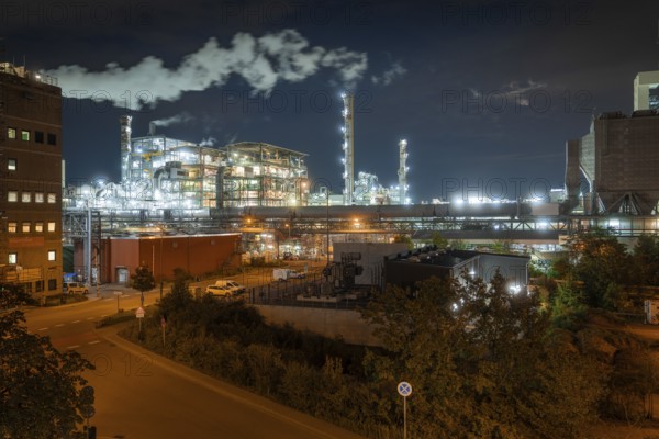 Large industrial plant at night with artificial lighting and steam, surrounded by urban environment, Mannheim, Germany, Europe