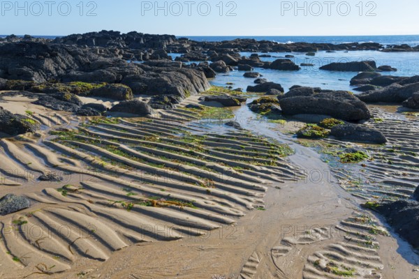 Rocks and sea with sandy wave patterns on the shore under a clear blue sky, Montedor, Viana do Castelo, Portugal, Europe