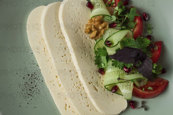 Sliced Imeruli cheese, Georgian cheese, with vegetables, top view, no people