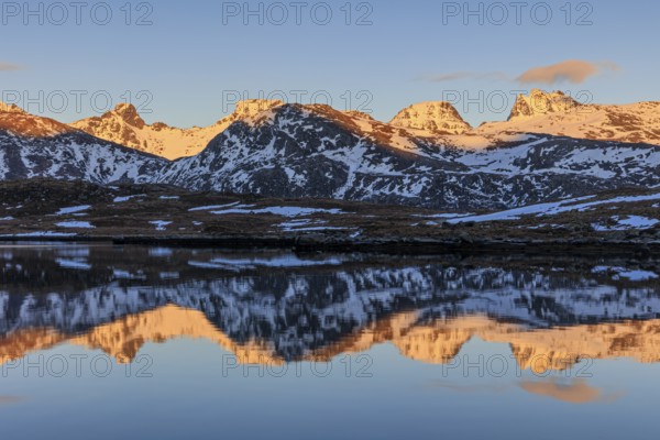 Steep mountains reflected in fjord, evening light, snowy, winter, Moskenesoya, Lofoten, Norway, Europe