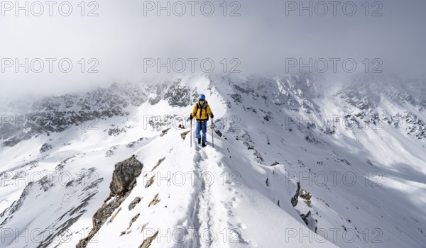 Mountaineer climbing up the narrow ridge of Piz Laviner, view of wintry mountain landscape, Grisons Haute Route, Albula Alps, Rhaetian Alps, Grisons, Eastern Switzerland, Switzerland, Europe