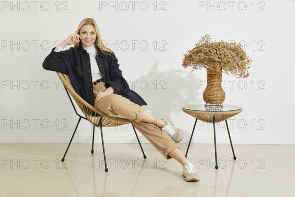 A cheerful woman poses comfortably in a stylish chair, her relaxed expression accentuated by the clean lines of the modern decor