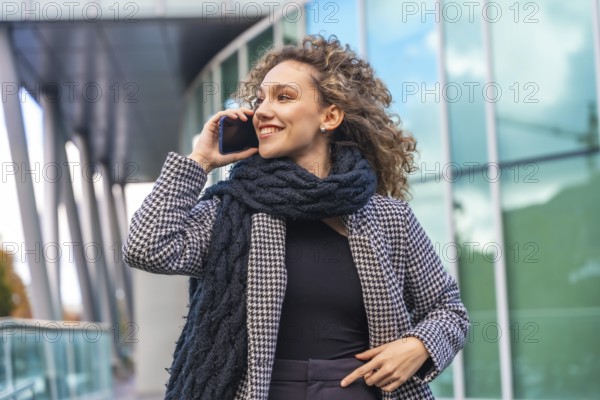 Beauty woman with curly hair and elegant clothes talking to the mobile outdoors