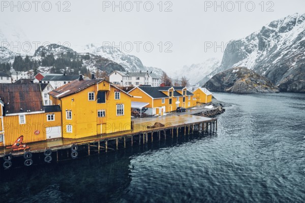 Panorama of Nusfjord authentic fishing village with yellow rorbu houses in Norwegian fjord in winter. Lofoten islands, Norway, Europe
