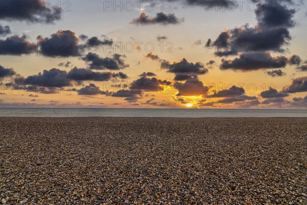 Empty pebble beach by the sea, sunset on the horizon