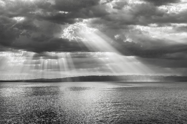 Tyndall effect over Lake Constance, sun rays break through cloudy sky and reflect on the water, Canton Thrugau, Switzerland, Europe