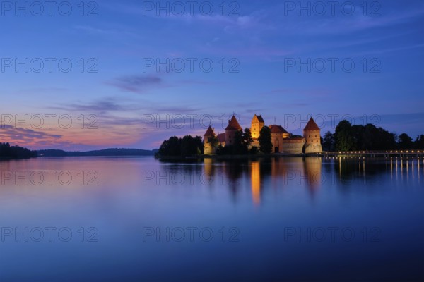 Trakai Island Castle in lake Galve illuminated in twilight reflecting in peaceful water, Lithuania, Europe