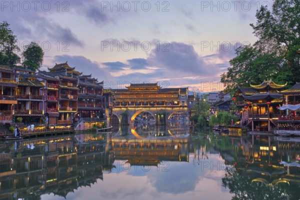 Chinese tourist attraction destination, Feng Huang Ancient Town (Phoenix Ancient Town) on Tuo Jiang River illuminated at night. Hunan Province, China, Asia