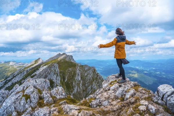 Mount Aizkorri 1523 meters, the highest in Guipúzcoa. Basque Country. Ascent through San Adrián and return through the Oltza fields. A young woman in yellow looking at the views on top