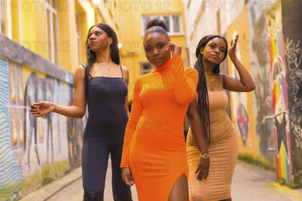 Fashionable urban style with three black African girls on a city street, tight dresses and seductive looks. Lifestyle girls of color