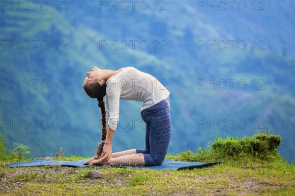 Yoga, outdoors young beautiful slender woman yoga instructor doing camel pose Ustrasana asana exercise outdoors