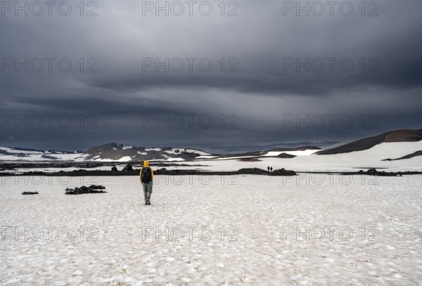 Hikers in snow-covered volcanic landscape with volcanic sand and petrified lava, crater of Askja volcano, Icelandic highlands, Iceland, Europe