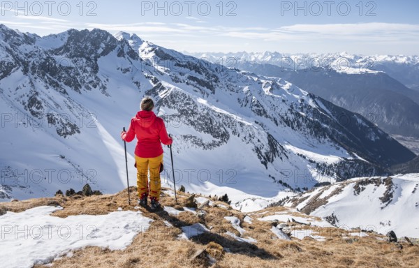 Ski tourer standing next to summit cross, summit of Mitterzeigerkogel in winter, Sellraintal, Kühtai, Tyrol, Austria, Europe