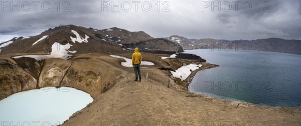 Tourist at the crater rim, crater lake Víti and Öskjuvatn in the crater of Askja volcano, volcanic landscape, mountain massif Dyngjufjöll, Icelandic highlands, Vatnajökull National Park, Iceland, Europe