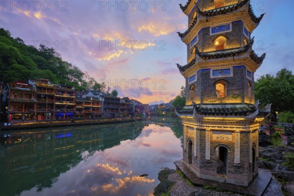 Chinese tourist attraction destination, Feng Huang Ancient Town (Phoenix Ancient Town) on Tuo Jiang River with Wanming Pagoda illuminated at night. Hunan Province, China, Asia