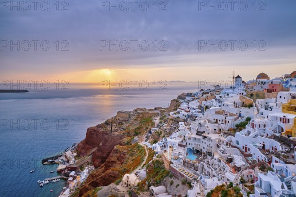 Famous greek iconic selfie spot tourist destination Oia village with traditional white houses and windmills in Santorini island on sunset in twilight, Greece, Europe